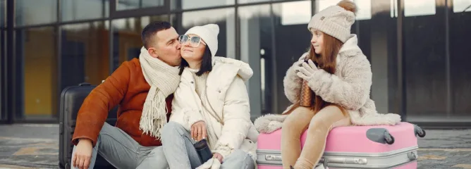 Папа целует маму а девочка сидит на чемодане