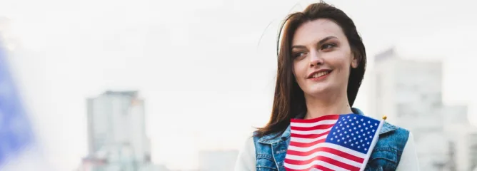 Девушка с темными волосами держит маленький флаг США