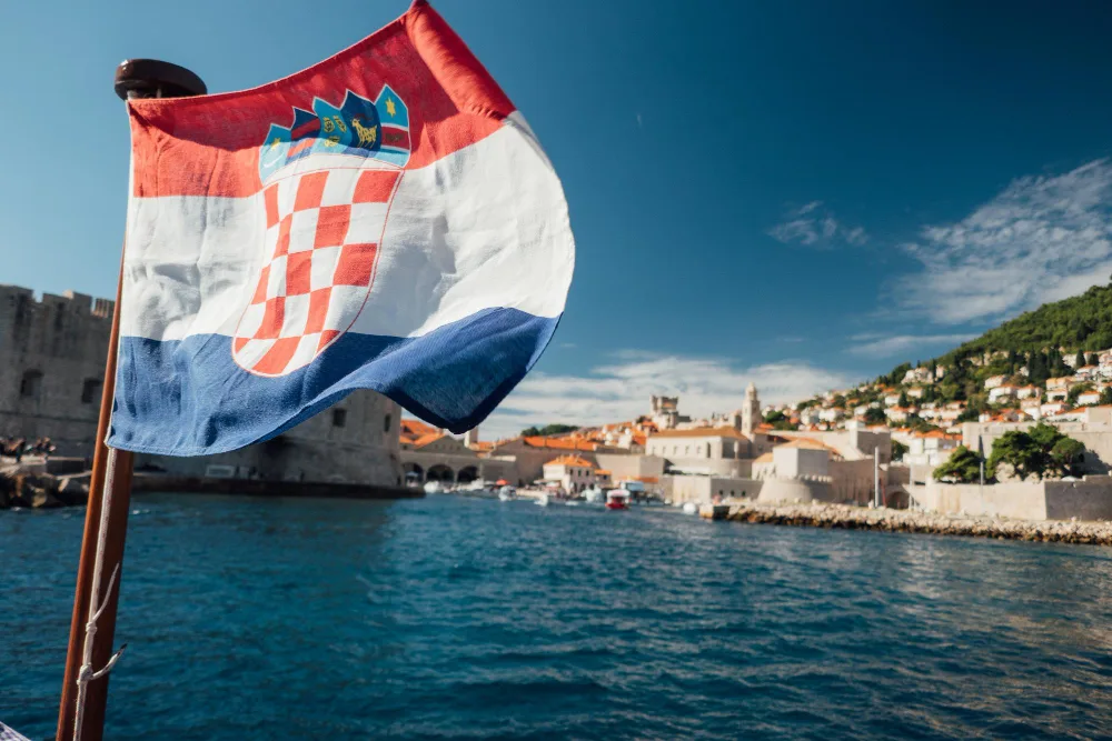 Развивающийся флаг Хорватии на фоне прибрежного города Хорватии