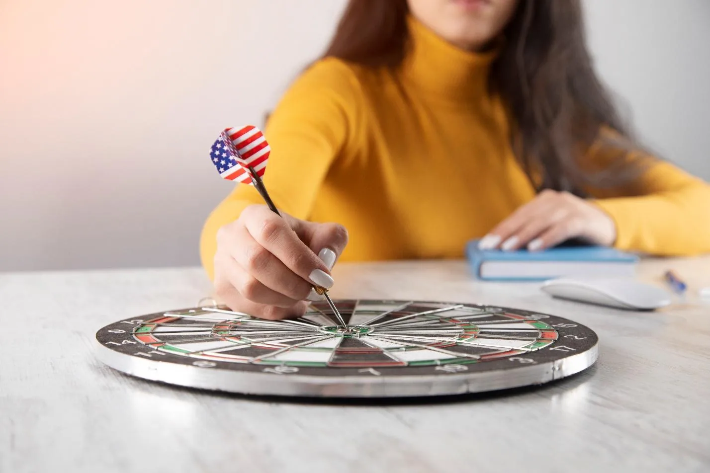 Девушка держит дротик с концом в виде флага США на мишени