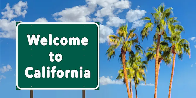 Знак Welcome to California на фоне пальм