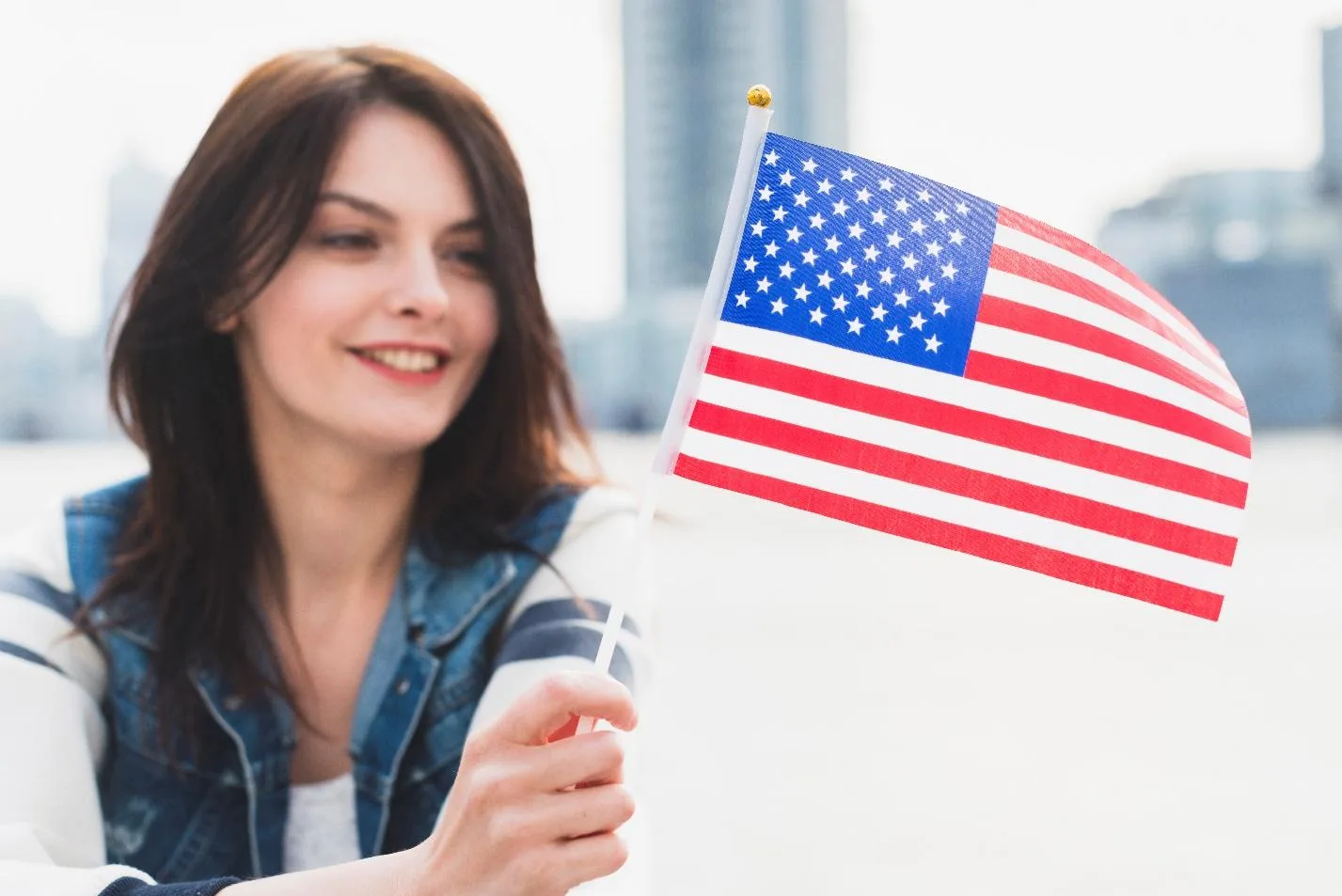 Девушка держит флаг США на фоне города